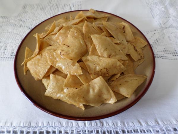 Totopos crujientes en un plato de barro sobre mantel de encaje